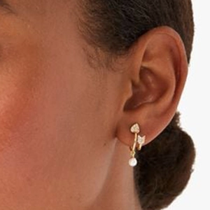 Macro view of gold heart arrow earring with hanging pearl shown on model's ear