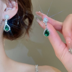 Macro detail of emerald green teardrop earrings with silver setting and sparkling stones