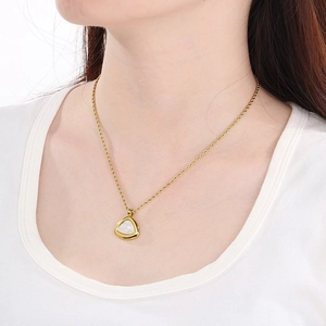 Gros plan d'un collier doré avec pendentif triangulaire blanc sur une chaîne torsadée