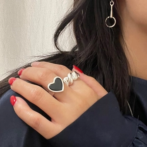 Close-up of a silver twist ring and heart-shaped black onyx ring set on a hand