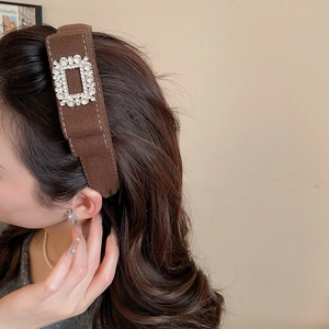 Detail of a brown suede headband with a sparkling rhinestone square buckle decoration