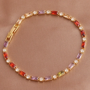 Macro detail of gold bracelet featuring colorful rectangular and round zircon gemstones