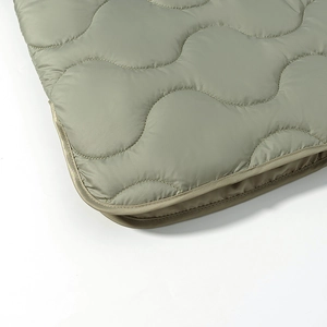 Detail of sage green quilted jacket fabric with wave pattern and high-quality stitching