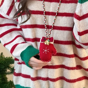 Detailed close-up of festive red glove pendant necklace with bell and bow for Christmas
