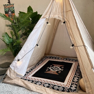 Bohemian woven outdoor picnic blanket used inside a minimalist canvas camping tent