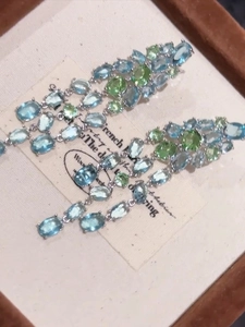 Macro shot of silver tassel earrings with blue and green oval zircons in a jewelry box