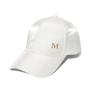 Detail of white satin baseball cap with golden metal M emblem and stitched brim detail
