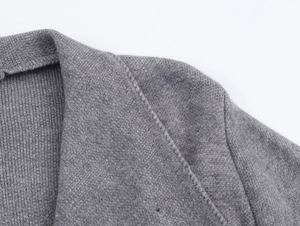 Macro shot of fine grey knit texture and shoulder stitching on a fashion cardigan coat