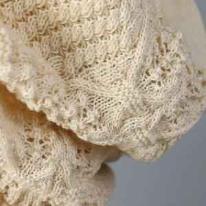 Detailed macro view of a cream-colored Japanese style openwork knit beanie headwear.