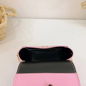 Pink mini crossbody bag with gold chain and bow, interior view on woven basket