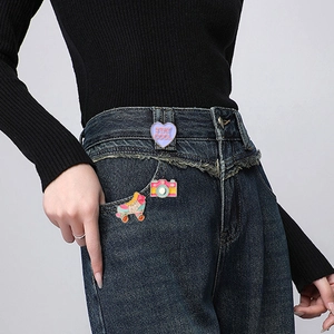 Détail de pins émaillés avec cœur, appareil photo et patins sur tissu en denim