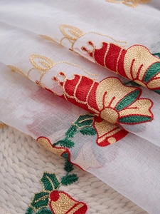 Detail of Christmas white curtain with red bells and green leaves embroidery patterns
