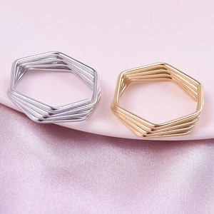 Detail of minimalist hexagonal multi-layer wire rings in gold and silver finishes