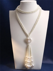 Detail of elegant double-layered pearl necklace with large heart pendant and tassel fringes