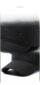 Detail of black winter baseball cap with knit texture and silver metal T logo