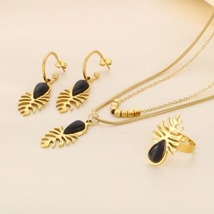 Détail d'une parure en or motif feuille avec collier oeil de chat noir, bague et boucles