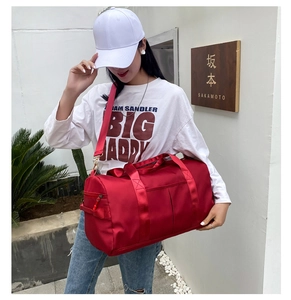 Outdoor shot of a red large capacity cylinder fitness bag with double handles and strap