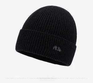 Close-up of black ribbed knit beanie showing high-quality embroidery and mountain logo detail