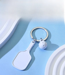 Detail of white pickleball paddle keychain with dinosaur sticker and silver ring