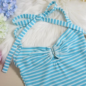 Detailed flat lay of blue and white striped knit halter top on plush white faux fur background