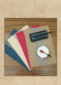 Detail of woven PVC table mats showing multiple colors and textures on a dark wooden table