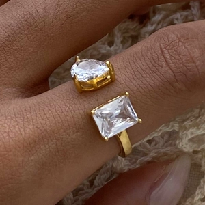 Detail of open gold ring with teardrop and rectangular zircons worn on a finger
