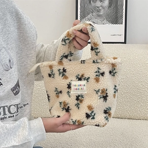 Close-up of floral plush tote bag with lamb wool texture and embroidered brand label