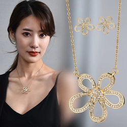 Detail view of a gold clover jewelry set featuring sparkling rhinestones on model