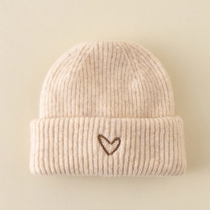 Detailed view of beige knit beanie featuring a brown heart embroidery on folded cuff