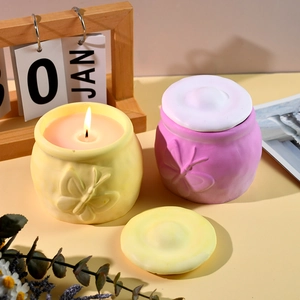 Detalle de frascos para velas con relieve de mariposa y una cálida llama encendida