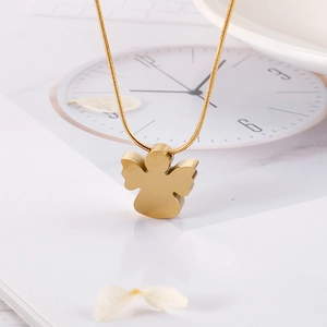 Close-up of golden angel necklace pendant set against vintage clock and flower petals