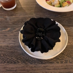 Detailed view of an elegant black lace flower hair claw clip on a white decorative plate