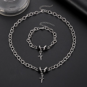 Macro shot of gothic silver chain with black rectangular gemstone and cross pendant detail