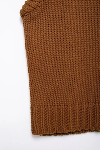 Close-up of caramel cable knit texture and ribbed hem detail on a sleeveless sweater vest