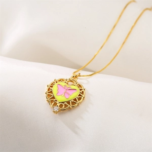 Detail of gold heart pendant with pink butterfly, yellow enamel and small rhinestone