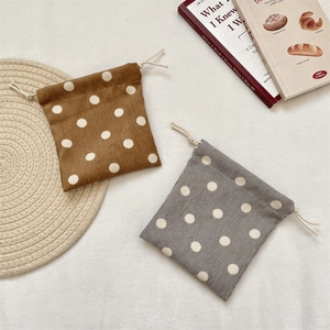 Detailed texture of polka dot corduroy drawstring storage pouches in brown and gray