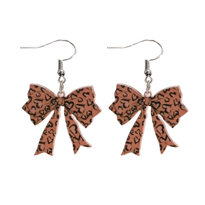 Detail of red bow earrings featuring leopard print and heart motifs with silver hooks