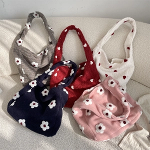 Dettaglio di borse tote in peluche con motivo floreale in vari colori su un divano