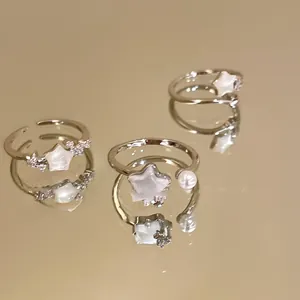 Detailed view of silver star rings with pearls and mother-of-pearl on a gold mirror