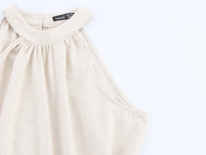 Detail des gefalteten Ausschnitts am beigen Leinenkleid mit Kokosnuss-Stickerei