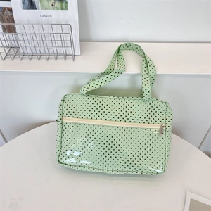 Detail of light green polka dot tote bag with a clear PVC front pocket and zipper closure