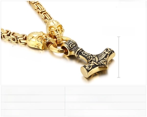 Close-up of golden Viking Mjölnir hammer pendant with skull details on a heavy chain
