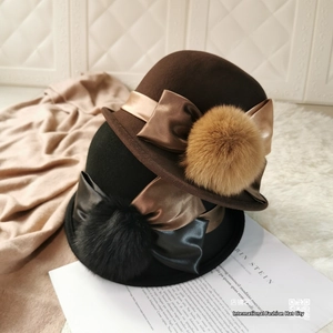 Close-up of wool felt bucket hats with satin bows and fluffy pom poms in brown and black
