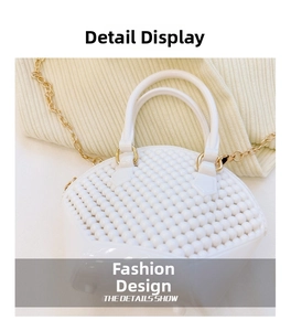 Close-up of white shell bag featuring beaded texture and gold chain strap detail