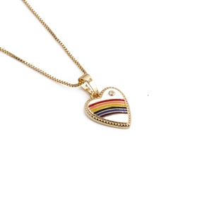 Detail of golden heart pendant with rainbow enamel stripes and a small sparkling gemstone