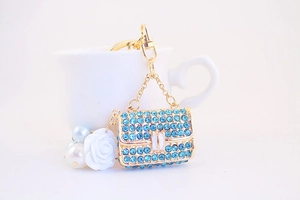Close-up of blue rhinestone handbag keychain with white pearls and camellia flower charm