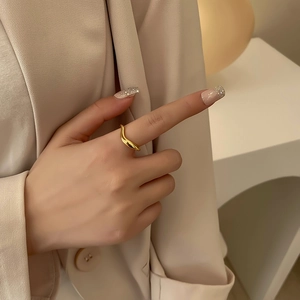 Minimalist gold wave ring featuring a sleek geometric design on a model's hand