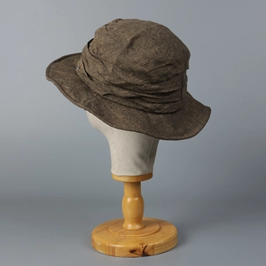 Detailed close-up of a brown distressed linen bucket hat displayed on a wooden stand