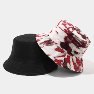 Detail view of double-sided bucket hats in solid black and colorful tie-dye patterns