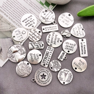 Macro shot of silver alloy charms with engraved motivational quotes for DIY jewelry